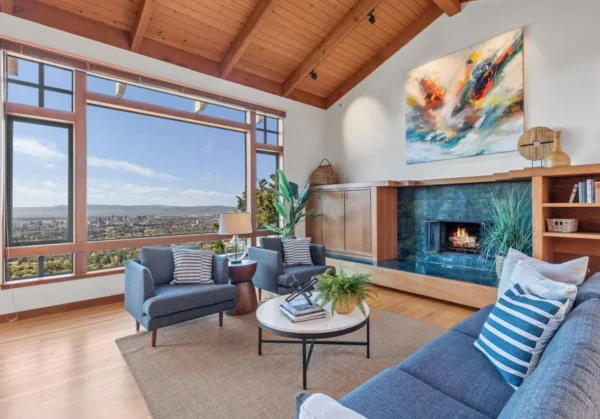 Modern living room in an El Cerrito hillside home featuring floor-to-ceiling windows with a panoramic view of the East Bay, high wood-beamed ceilings, and contemporary furniture.